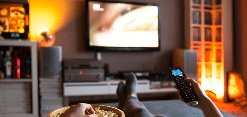 uma sala de estar com uma pessoa trocando de canal na televisão