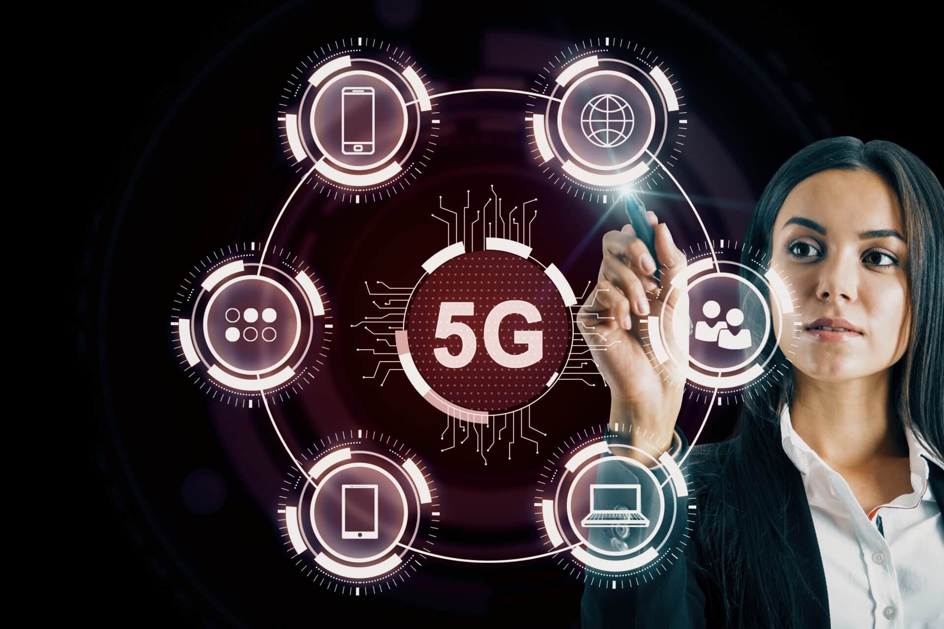 Uma mulher de negócios, com cabelos escuros e vestindo um blazer preto, interage com uma interface digital futurista em um fundo escuro. Ela utiliza uma caneta digital para tocar em um dos ícones de um diagrama circular que tem o destaque "5G" ao centro.