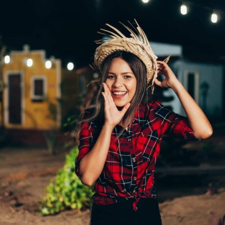 uma jovem com camisa xadrez e chapéu de palha