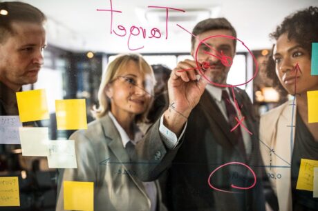 4 executivos em frente a um quadro esrevendo planos