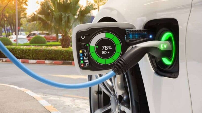 Um conector de carregamento de cor preta e iluminado por uma luz verde está inserido na porta de carga do carro. Um display digital na porta mostra que a bateria está com 78% de carga. O cabo de recarga é azul.