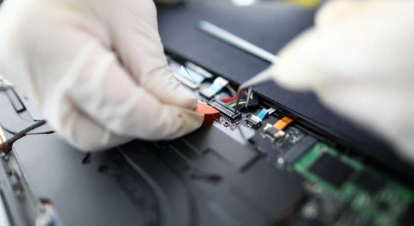 Técnico com luvas realizando manutenção em placa de circuito eletrônico